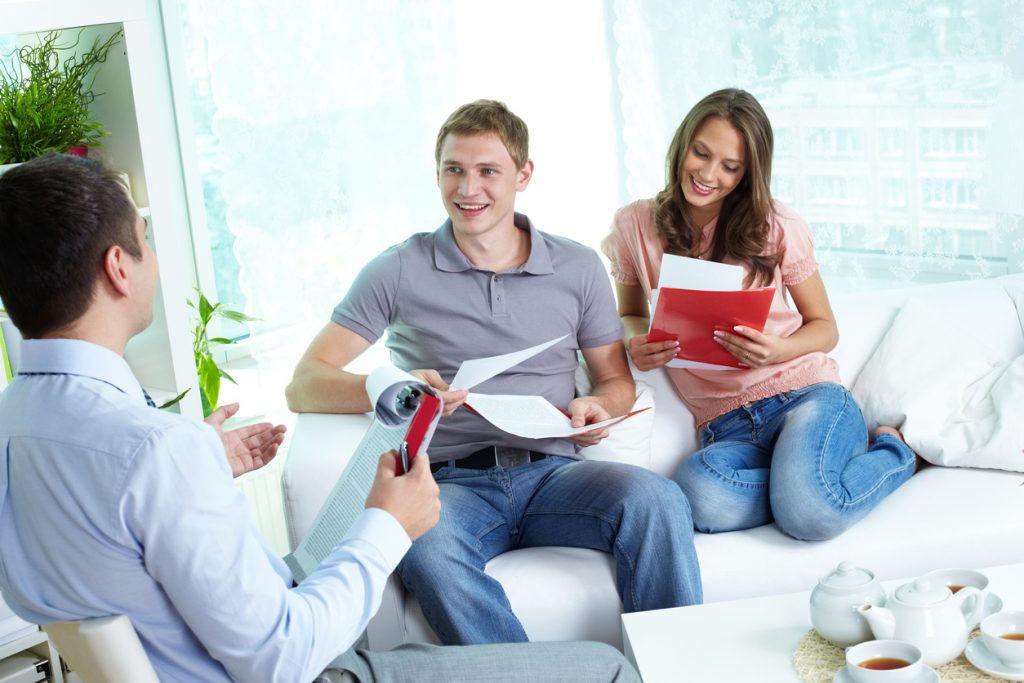 Young family reading insurance contract, their agent advising